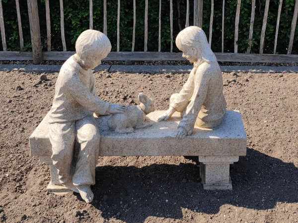 Stone carving of a boy girl and rabbit